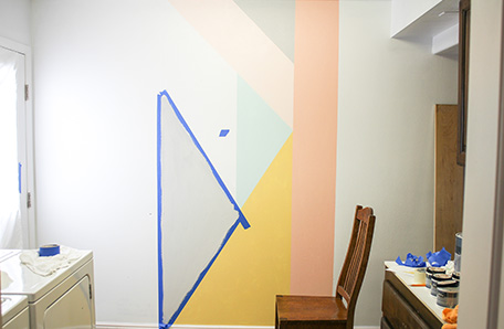 partially finished accent wall with geometric patterns and tape