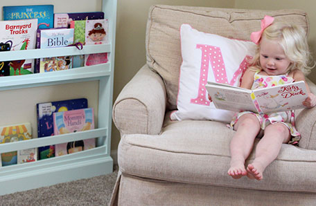 bookshelf and girl sitting in chair reading