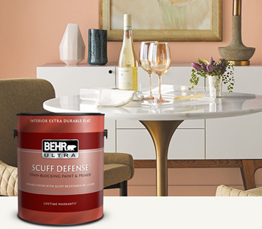 Mobile version of dining room with a peach colored wall and a can of Behr Ultra Scuff Defense Interior Extra Flat Paint in the foreground