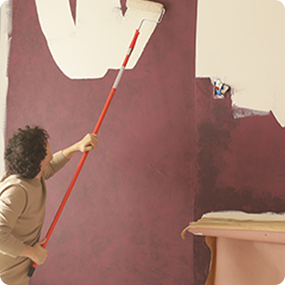 A person painting a wall with extension roller