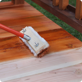 A stain pad applying stain to a deck