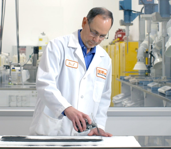 A Behr employee in a lab coat putting dirt on a surface to test