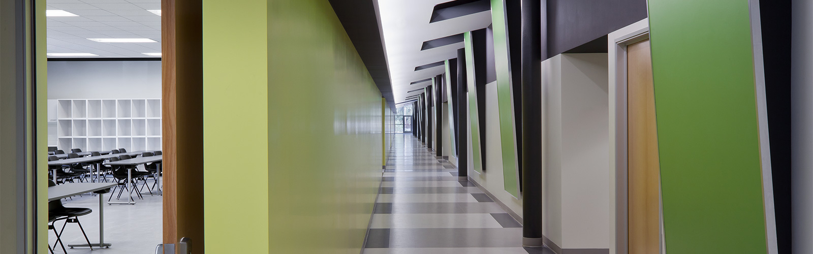 An image of a large empty classroom hallway with a green, gray and white color combination.