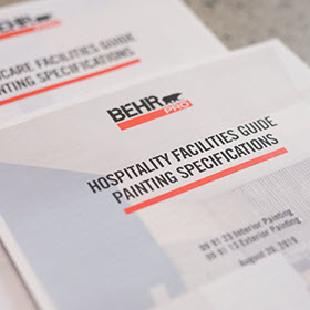 Close up images of a BEHR PRO document for Hospitality Facilities Guide Painting Specification on a table.