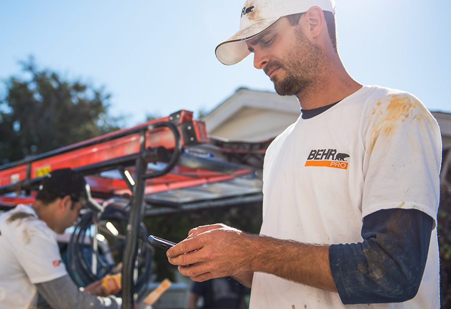 Painting contractor with a BEHR PRO shirt checking his mobile phone