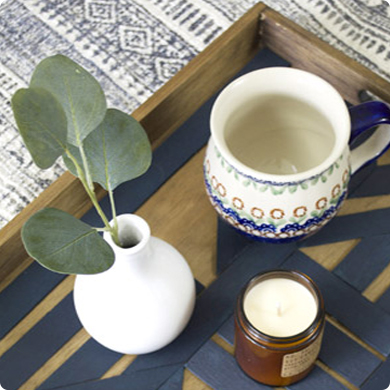 A tea cup and a small vase and a white candle on a table