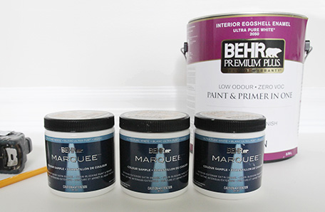 three small cans of paint in front of large can of primer