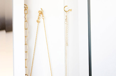 jewelry hanging on brass hooks in mirror storage