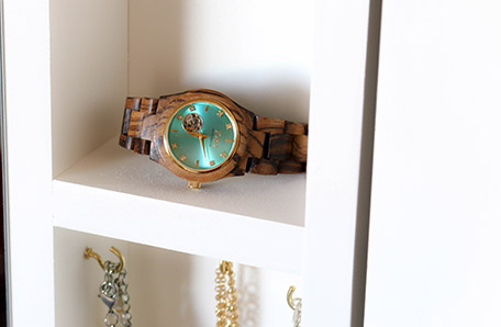 wrist watch sitting on shelf of mirror storage