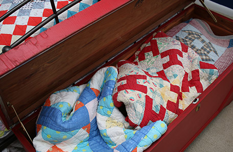 open red blanket chest with quilts inside