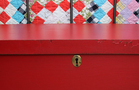 front view of red blanket chest with gold key plate