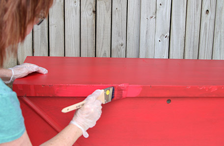 second coat of red paint being applied to blanket chest