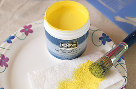 stencil brush beside small open can of yellow paint