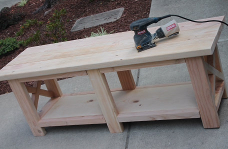 wooden bench with storage area being sanded
