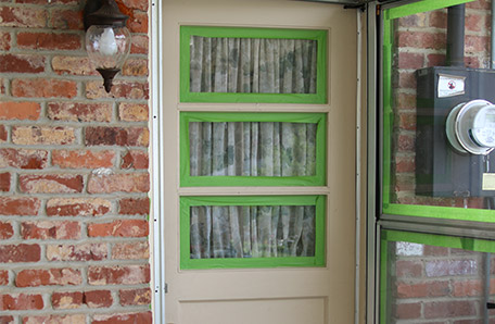 storm door with painters tape around glass panes