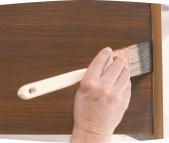 A person staining an end table with a paint brush