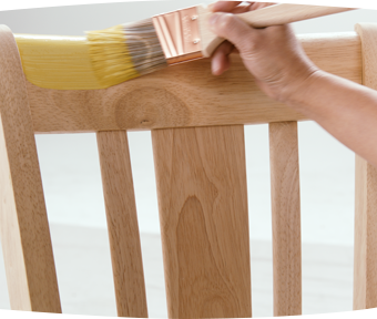 A person painting a wooden chair with a paint brush