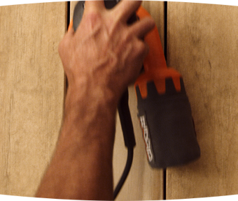 Person using an electric sander on a deck