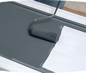 Person rolling paint onto a cabinet door with a BEHR® Premium Flocked Foam Roller.