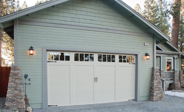 Image of exterior of a garage and garage door with teal siding.