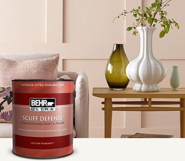 Living room with a pale peach colored wall and a can of Behr Ultra Scuff Defense Interior Paint in the foreground mobile image.