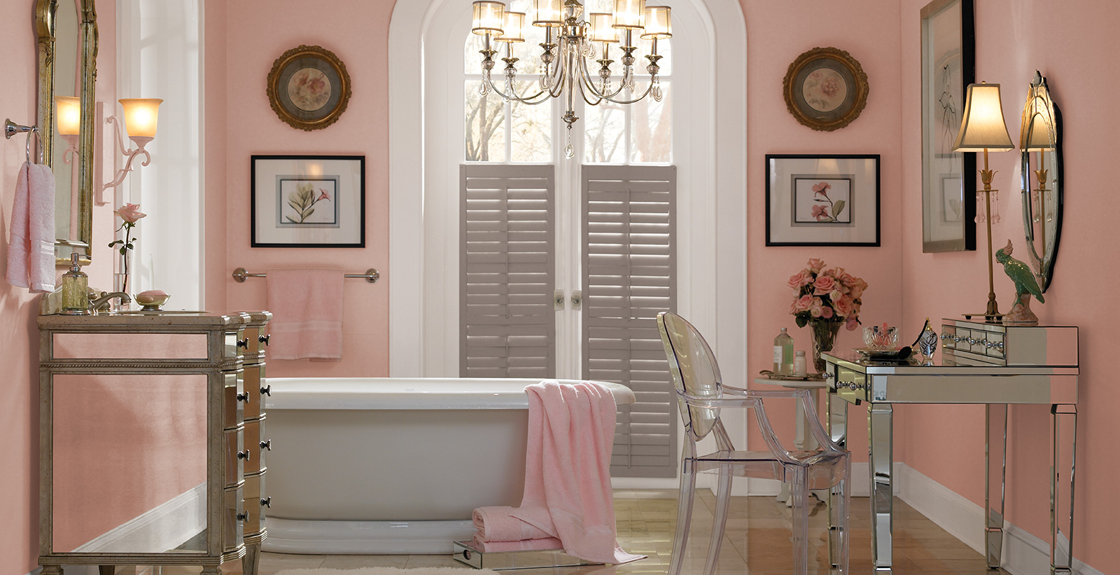 Classic styled, glamour bathroom with pink walls, white trim, brown shutters, vintage vanity and mirror.