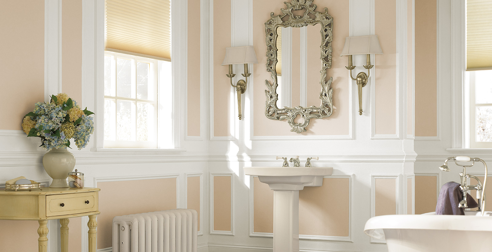 Inviting roman themed bathroom with orange walls, white trim, white sink, and rectangular mirror.