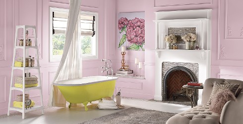 Inviting themed bathroom with pink walls, pink trim, yellow bathtub, and white fireplace.