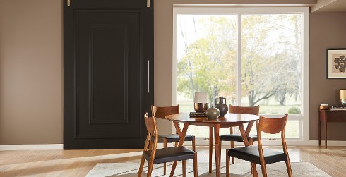 Open dining space in front of sliding doors, walls painted in warm tan color with white trim, sliding barn door in espresso black.