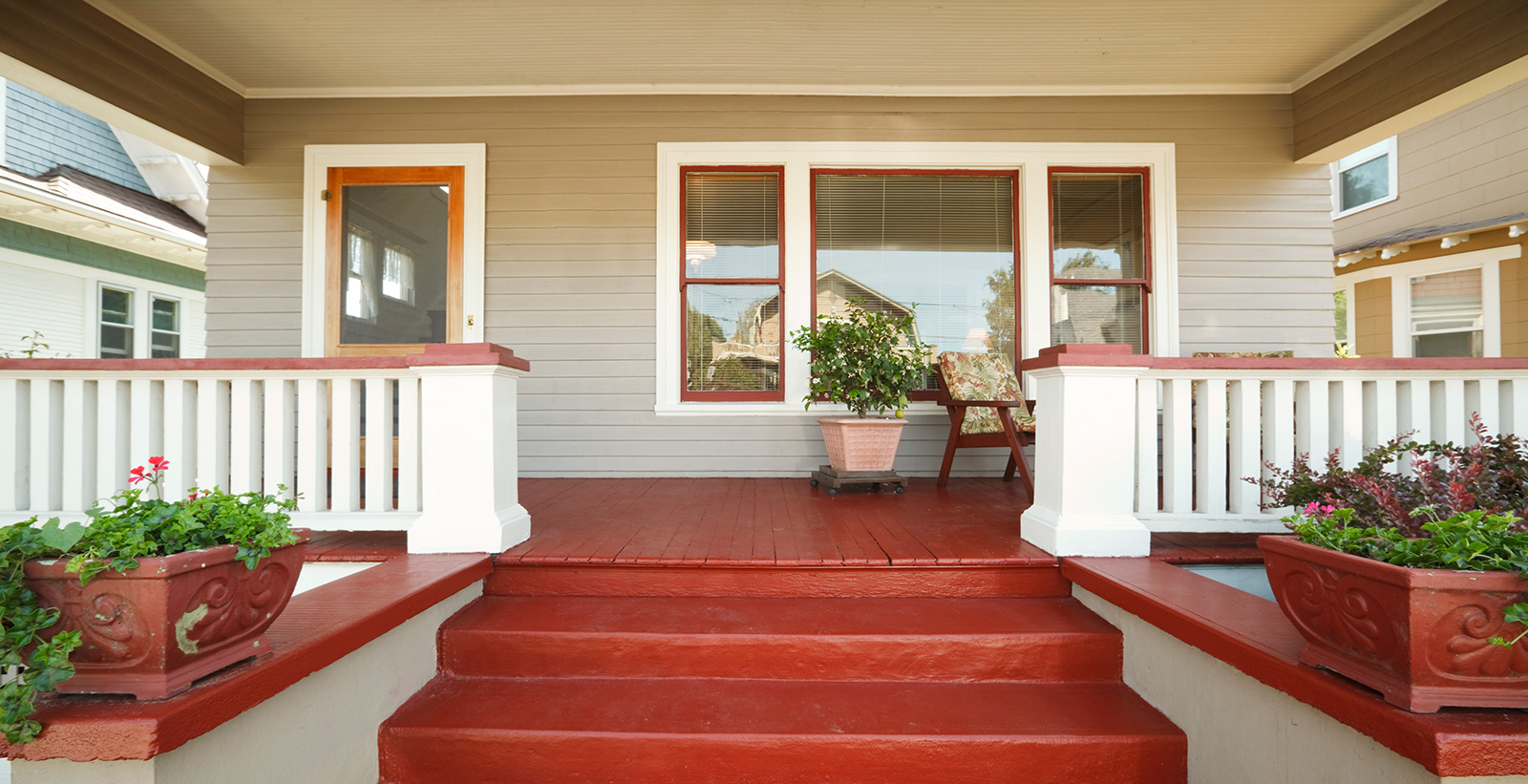 Inspirational house porch with red stairs, red flooring, white fencing, neutral walls, red planters and white trim.