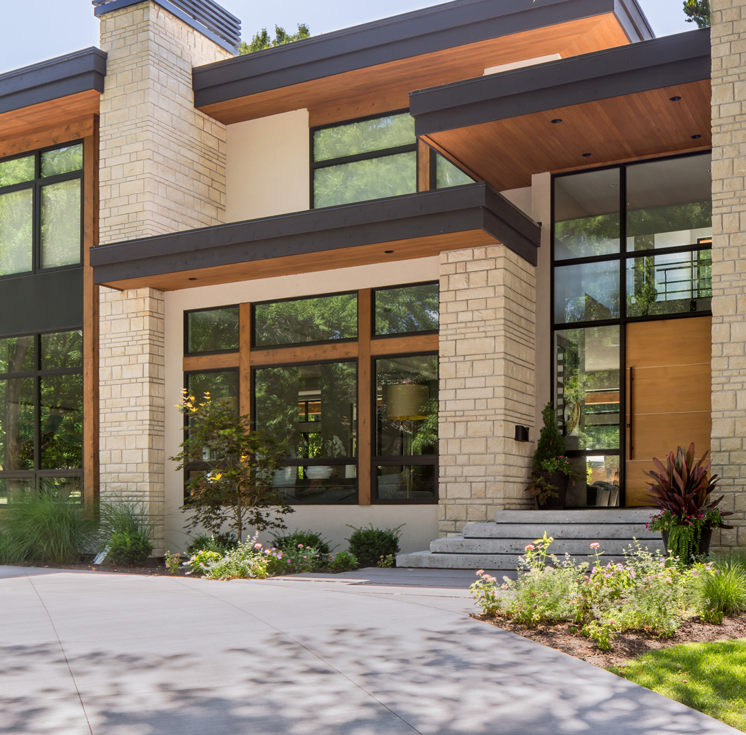Mobile-sized image of modern brick house with expansive glass windows.