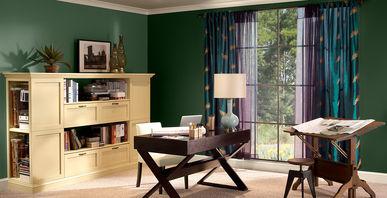 Office workspace with green walls, white trim, and wood furniture, bold and dramatic style.