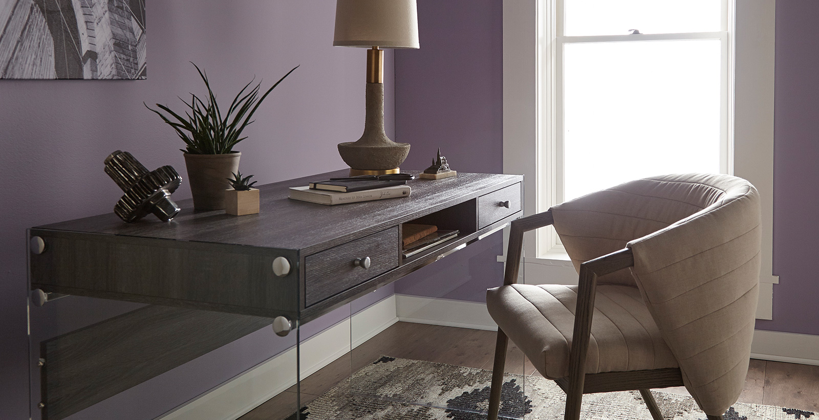 Office workspace with purple walls and white trim, wooden desk, relaxed and calming style.
