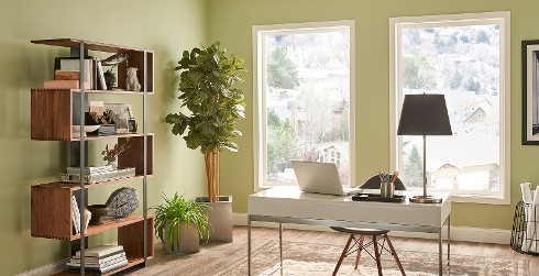 Office workspace with green walls and white trim, white desk, relaxed and calming style.