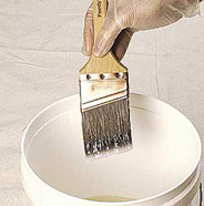 Brush being dipped in pail of paint or primer