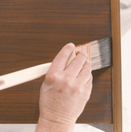 Person applying second coat of wood stain with paint brush