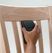 Person sanding a wooden chair with a sanding block