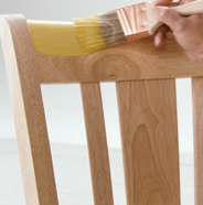 Person applying stain to a wooden chair