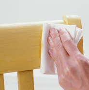 Person using a lint-free cloth to wipe excess stain off chair