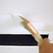 Person applying primer on a wall with a paint brush