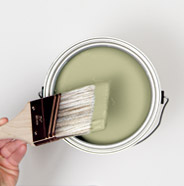 Person dipping a paint brush into a can of BEHR Paint