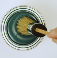 Person dipping a BEHR Chalk Decorative Paint Brush into a can of BEHR Chalk Decorative Paint