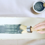 Person painting a dresser drawer with a BEHR Chalk Decorative Paint Brush