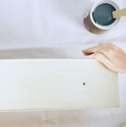 Person laying dresser drawers flat over a drop cloth