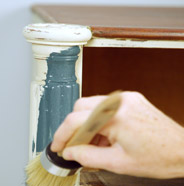 Person painting furniture with a BEHR Chalk Decorative Paint Brush