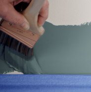 Person painting along painter's tape with an angled sash brush