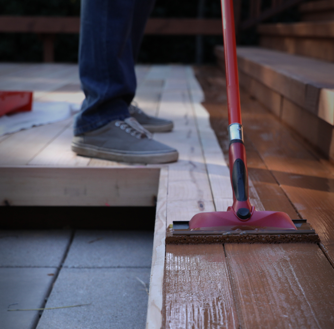 Mobile image of close up of stain being applied to a deck.