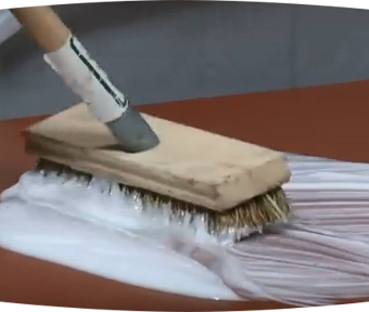 A brush scrubbing a white paint like substance onto flooring