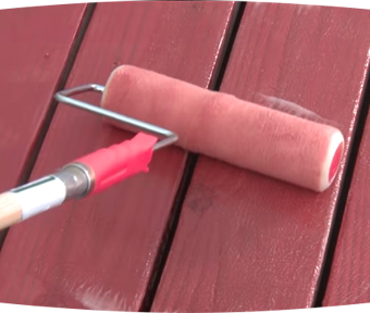 Paint roller painting a wood deck