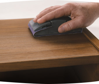 Person sanding a wooden end table with sanding block